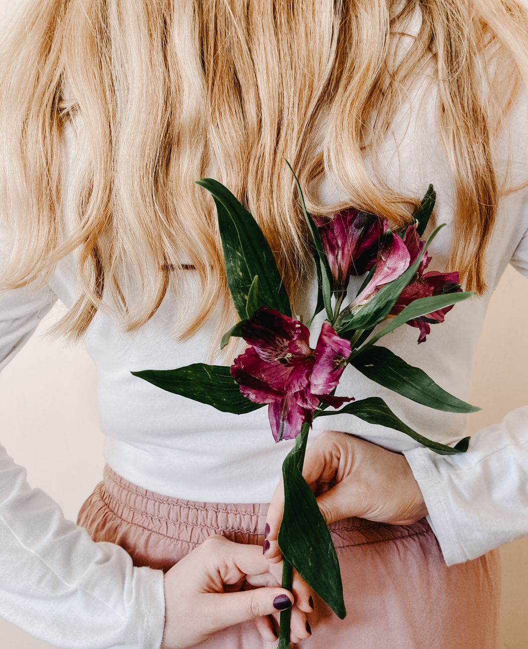 woman holding flower behind back